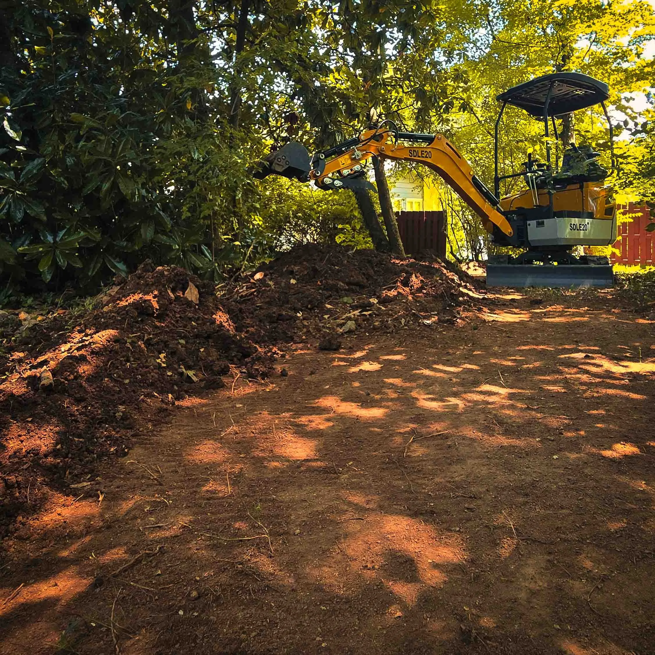 Mini excavator clearing a shaded backyard, Oak Ridge, TN