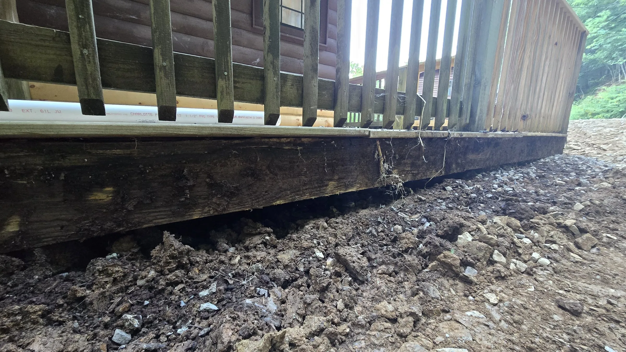 Soil and gravel piled against the deck framing