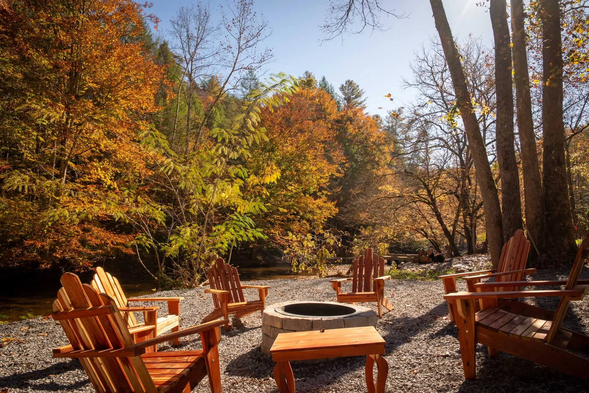 Stone fire pit on a gravel patio by the creek